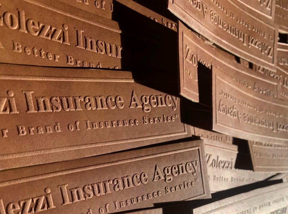 Embossed brown leather tags reading 'Zolezzi Insurance Agency: A Better Brand of Insurance Service