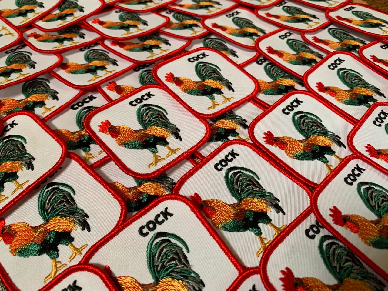 Square embroidered patches featuring a colorful rooster in green, orange, and red tones