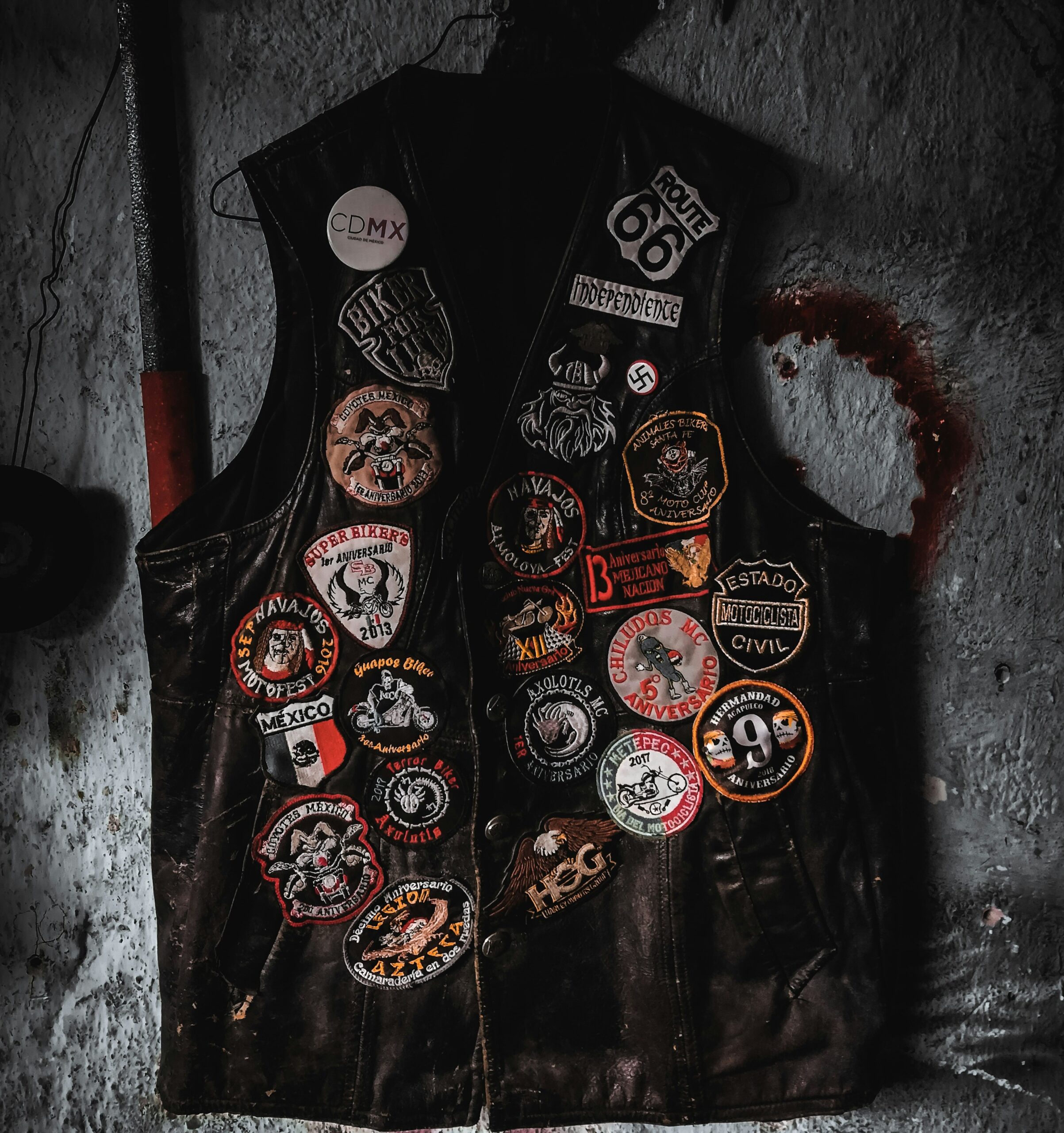 A black leather biker vest adorned with a variety of colorful embroidered patches